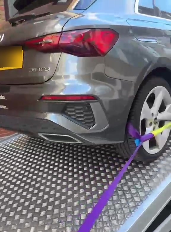 A wheel strap ratcheted over the tyre of a car on the MPG Recovery bed